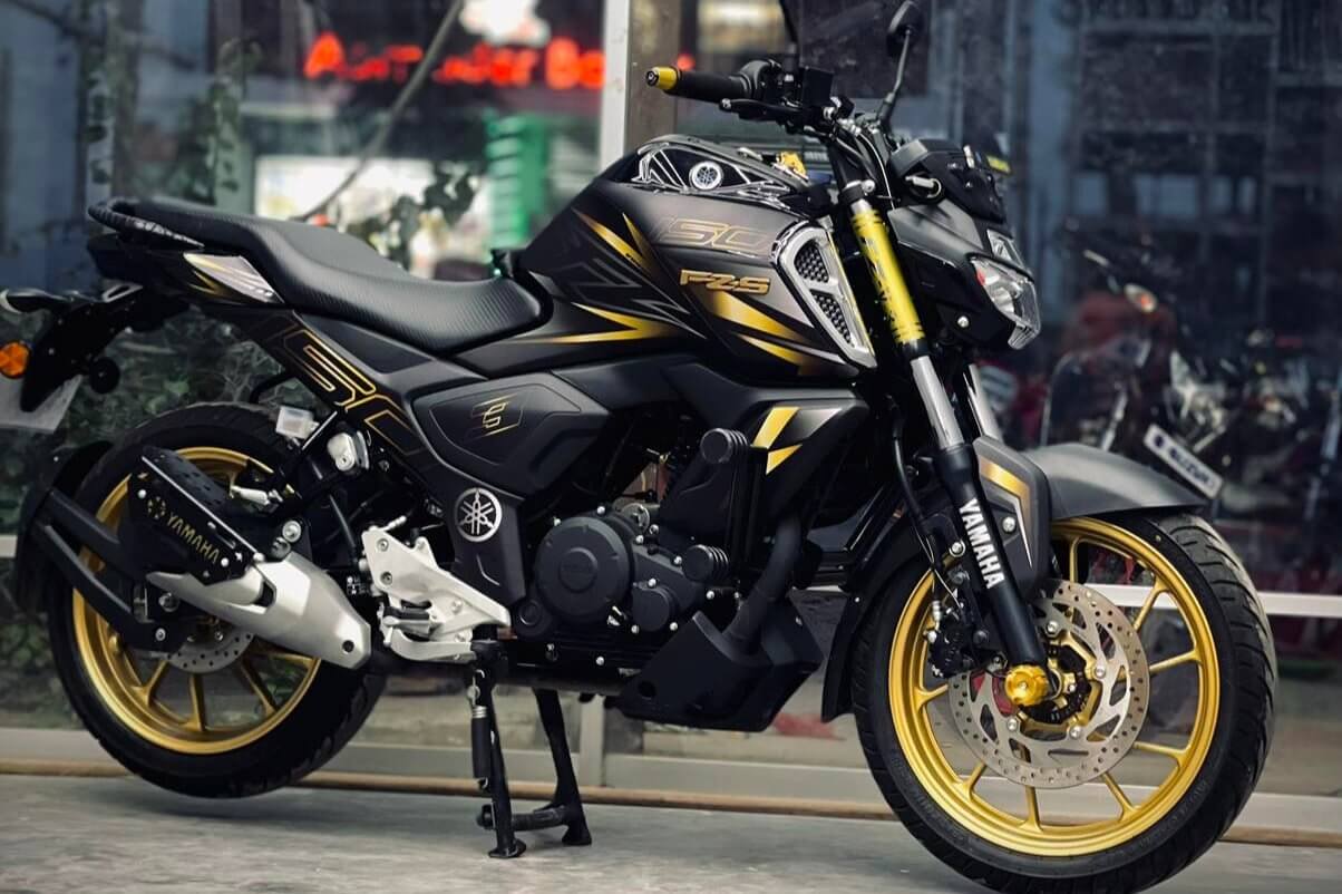 YAMAHA FZS V3/V4 motorcycle in a showroom, featuring black and gold detailing with visible branding and sporty design.