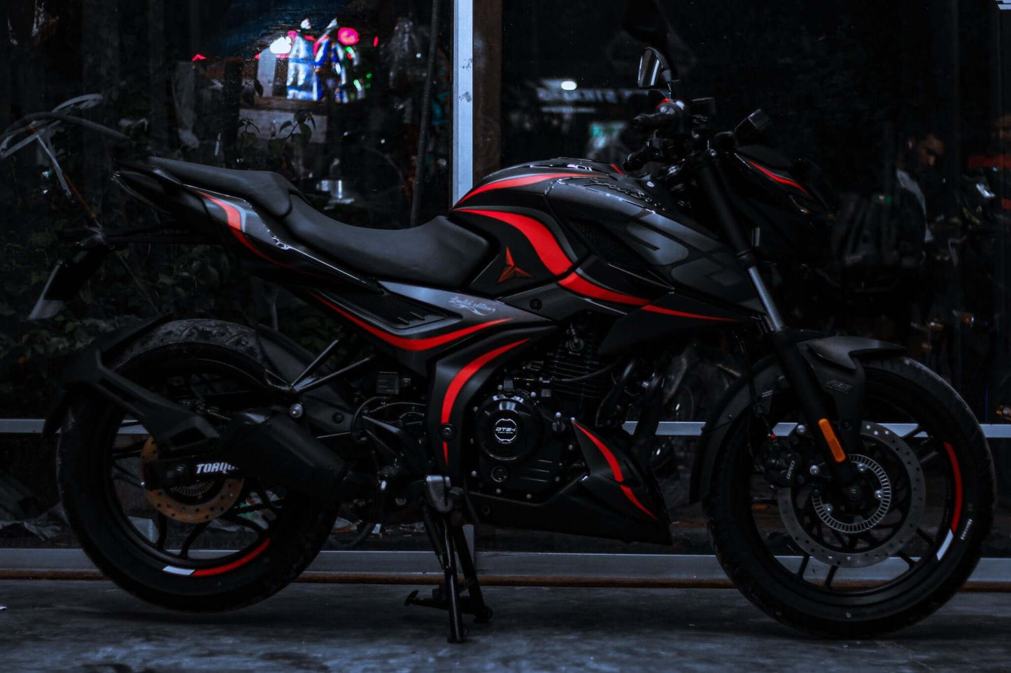 N160 motorcycle with a Wave Decal Kit featuring sleek red and black design highlights, parked indoors.